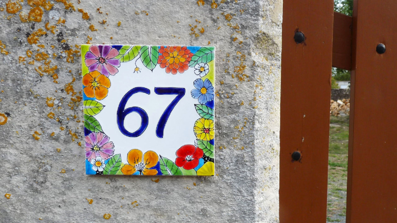 Numéro de maison céramique fleurs de toutes les couleurs numéro d'exemple : 67 sur mur en pierre