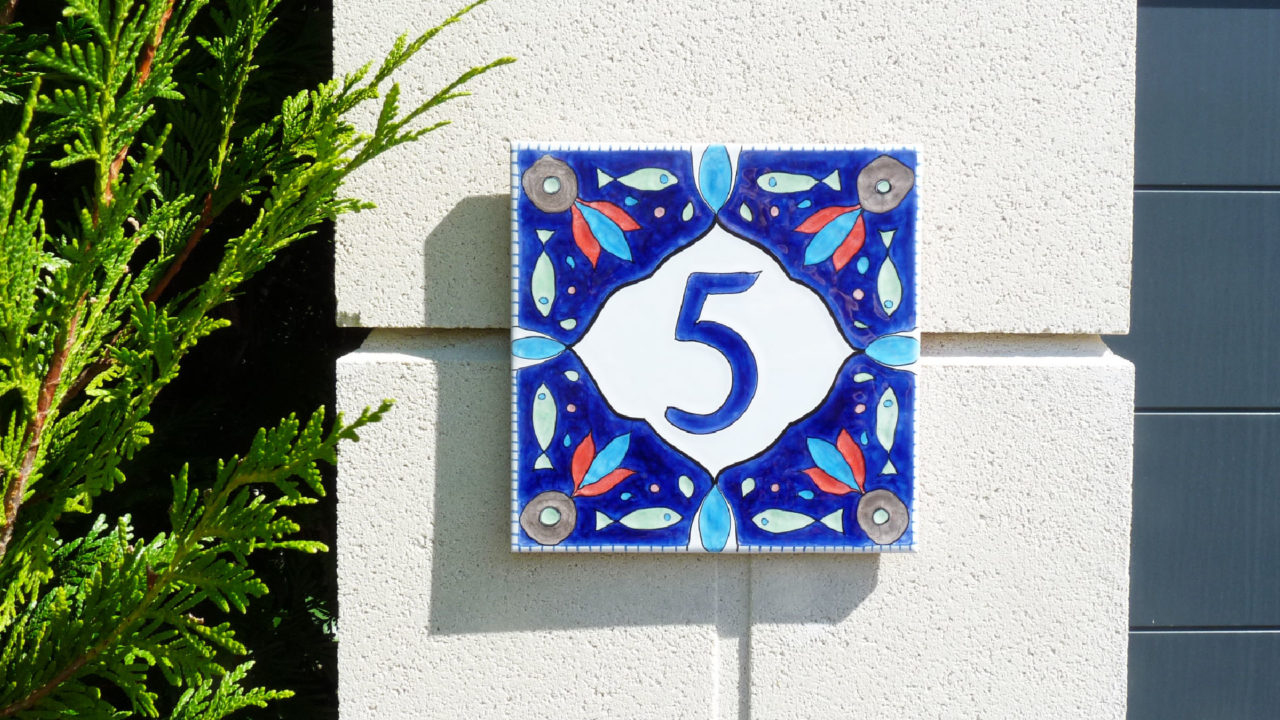 Numéro de maison céramique design poissons motifs symétriques bleus vert avec pointes de rouges sur portails blanc moderne maison