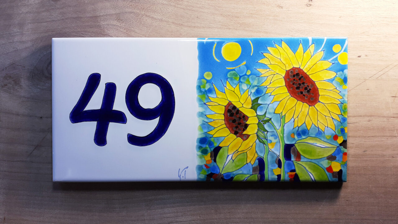 Numéro de maison céramique tournesols abstrait, couleurs vives jaunes et bleus, numéro d'exemple 49 sur table en bois.